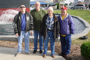 Group of men standing outside, in front of a water fountain