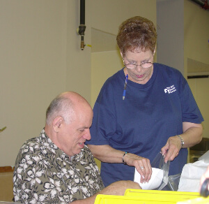 Woman helping man place papers inside plastic bags